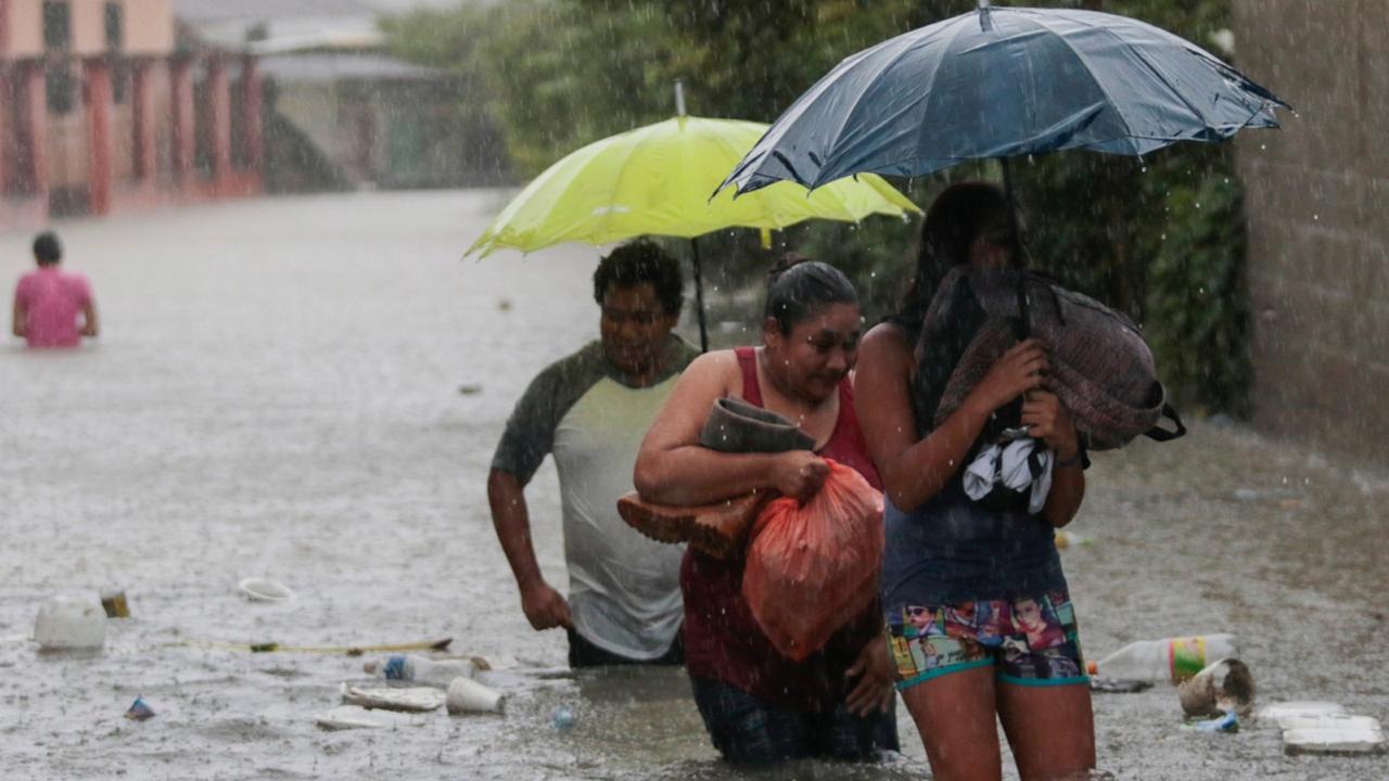 Residents wade through a flooded road carrying some belongings, in Progreso Yoro, Honduras, Wednesday, November 4, 2020. Eta weakened from the Category 4 hurricane to a tropical storm after lashing the Caribbean coast for much of Tuesday, its floodwaters isolating already remote communities and setting off deadly landslides. (AP Photo/Delmer Martinez)
