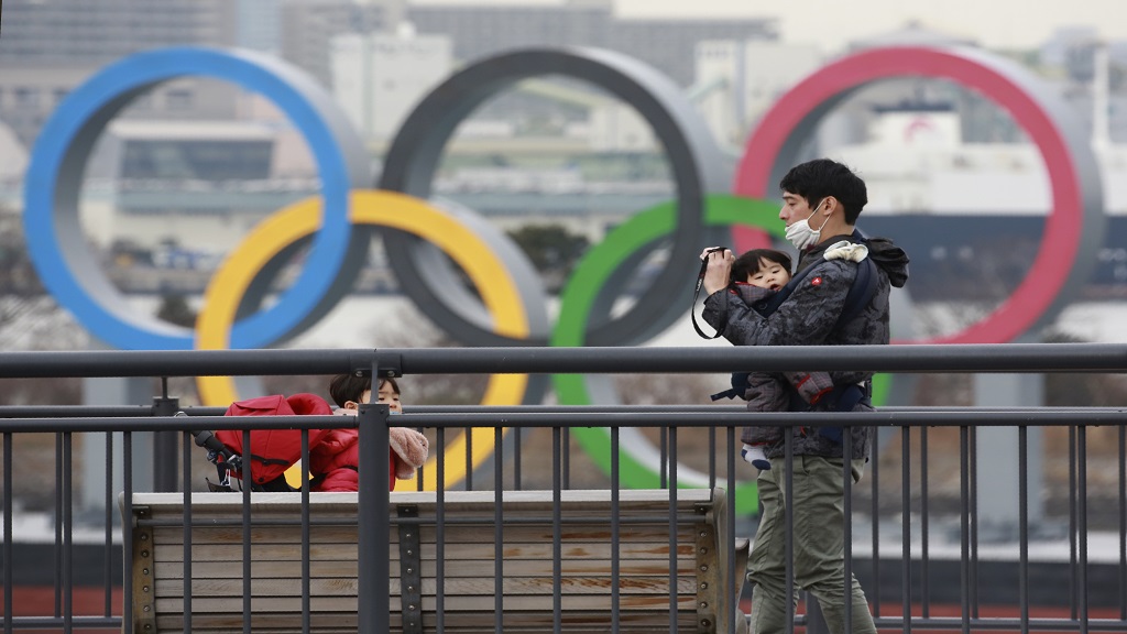 People wearing face masks to protect against the spread of the coronavirus stand at the Odaiba waterfront as Olympic rings is seen in the background in Tokyo, Tuesday, Jan. 26, 2021. (AP Photo/Koji Sasahara).


