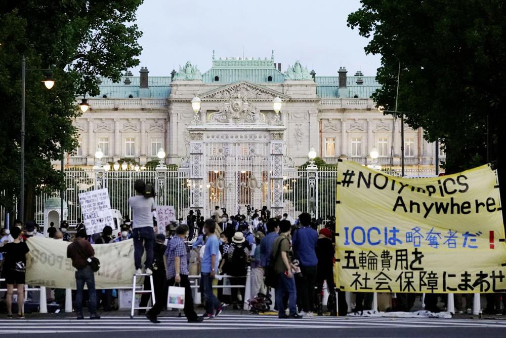 反对东京奥运会的抗议者聚集在阿卡萨卡宫外，日本州宾馆外国屋苑托马斯·巴赫及其官员在日本东京，日本，7月18日，2021年7月18日举行。横幅，黄色，阅读“IOC是一个Looter！为社会福利使用奥林匹克费用“。（Koji Harada / Kyodo News通过AP）