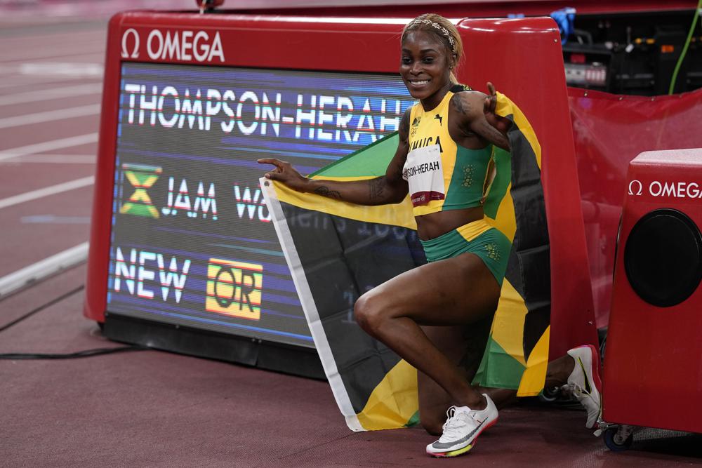 2021年7月31日周六，在东京举行的2020年夏季奥运会女子100米决赛中，牙买加选手伊莱恩·汤普森-赫拉在时钟前摆姿势拍照。(美联社图片/大卫·j·菲利普)