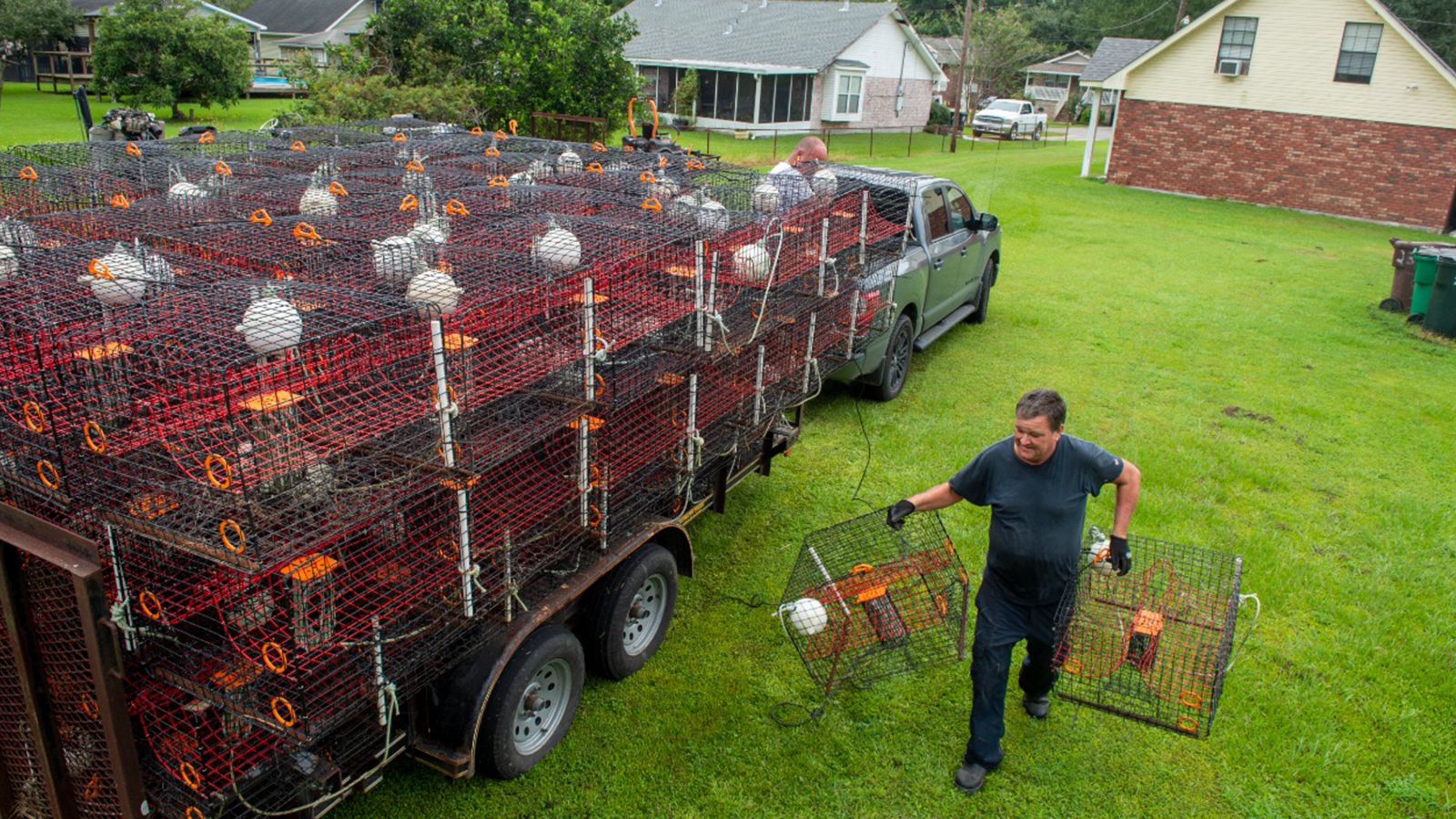Ray Guenther, 55, bottom right, helps his brother, John, 56, unload about 400 crab traps that he had to pull out of the water and move via flatbed trailer to dry land near his home in eastern St. Bernard Parish as the Louisiana coast prepares for the arrival of Hurricane Ida on Friday, August 27, 2021, in New Orleans. (Chris Granger/The Times-Picayune/The New Orleans Advocate via AP)