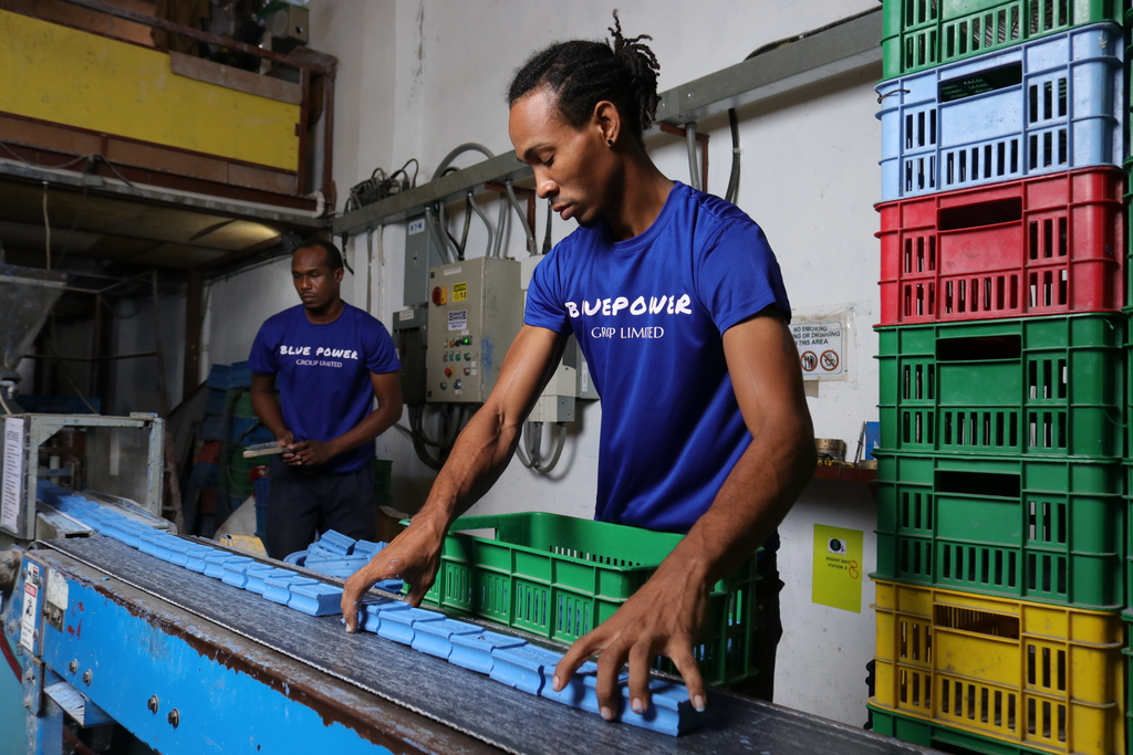 Contributed photo shows two Blue Power workers sorting soaps on the company's production line.