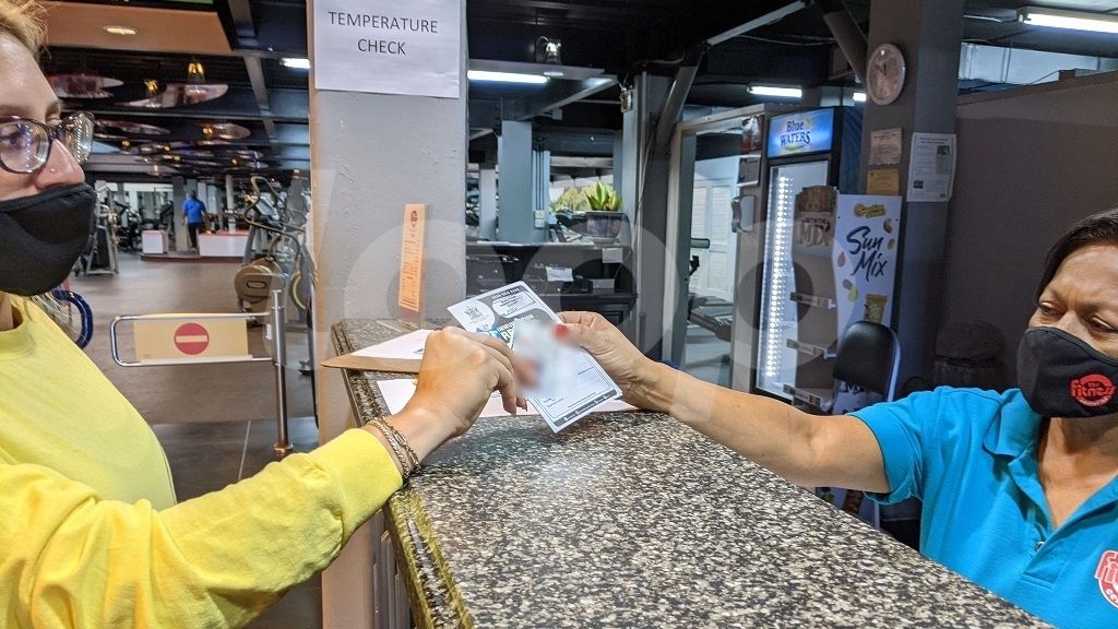 A Fitness Center patron shows their vaccination card, identification and membership card upon entry. The new safe zone policy began on October 11, 2021, where fully vaccinated patrons over 12 can enter gyms, casinos, theatres, dine-in restaurants, and more. Photo: Alina Doodnath 