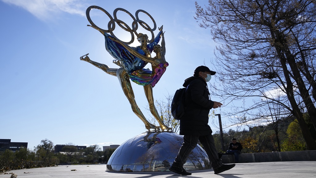 A visitor to the Shougang Park walks past the a sculpture for the Beijing Winter Olympics in Beijing, China, Tuesday, Nov. 9, 2021. China on Monday, Dec. 6, 2021, threatened to take "firm countermeasures" if the U.S. proceeds with a diplomatic boycott of February's Beijing Winter Olympic Games. (AP Photo/Ng Han Guan).