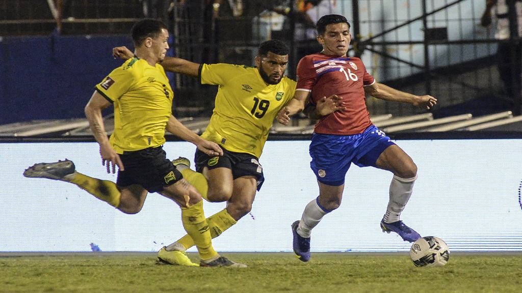 Costa Rica's, Alonso Martinez, right, fights for the ball with Jamaica's Adrian Mariappa, centre, during a qualifying football match for the FIFA World Cup Qatar 2022 at the National stadium in Kingston, Jamaica, Wednesday, Feb. 2, 2022. (AP Photo).

