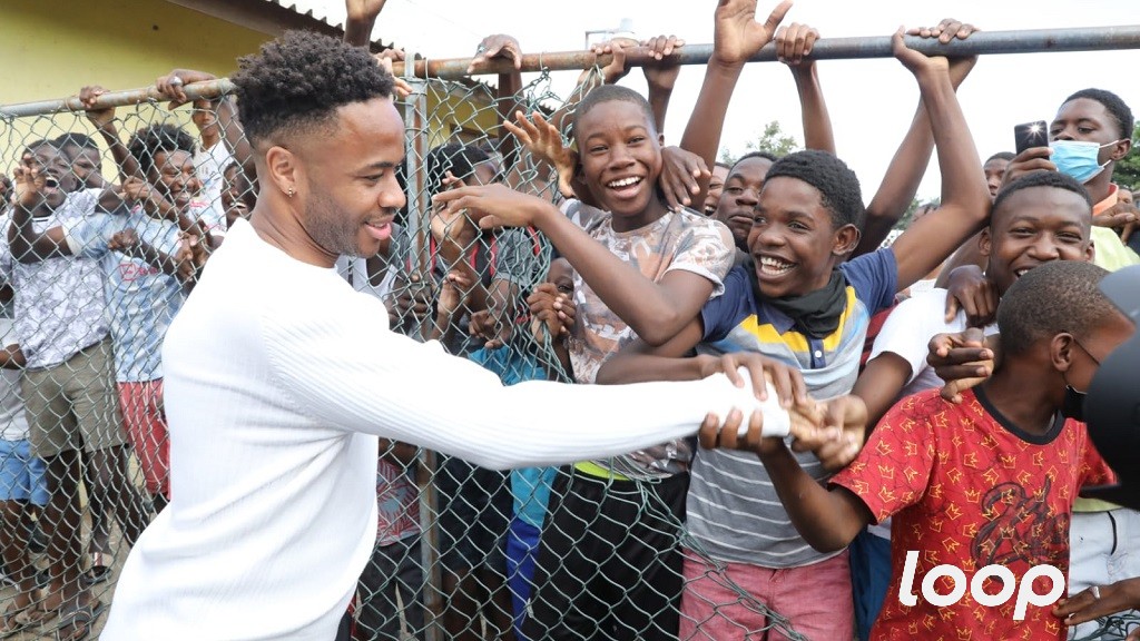 Raheem Sterling greets people gathered at Vin Lawrence Park in Trench Town, St Andrew on March 22, 2022 ahead of a friendly football match that is part of Prince William and Kate's official visit to Jamaica. (Photo: Marlon Reid)