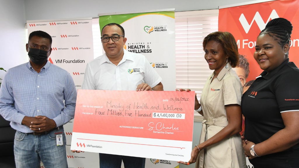 Samantha Charles, CEO - VM Foundation (2nd right) is joined by Shamalla McGregor, Financial Services Specialist - VMBS (right), in handing over a symbolic cheque valued at $4.5 million to Courtney Cephas, Executive Director, Philanthropic Mobilization - Ministry of Health and Wellness; and Dr Christopher Tufton, Minister of Health and Wellness, to commemorate its continued support of the Ministry’s Adopt-a-Clinic Programme. 