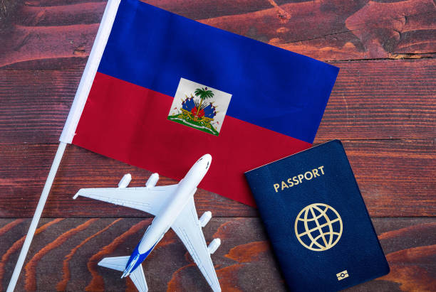 Passeport accompagne d'un petit drapeau haïtien et d'un petit avion. iStock.