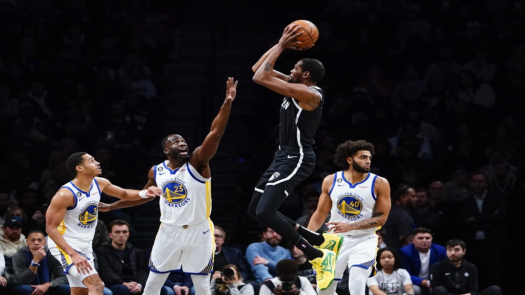 Golden State Warriors' Draymond Green (23) and Jordan Poole (3) defend a shot by Brooklyn Nets' Kevin Durant (7) during the first half of an NBA basketball game as teammate Anthony Lamb (40) watches Wednesday, Dec. 21, 2022 in New York. (AP Photo/Frank Franklin II).