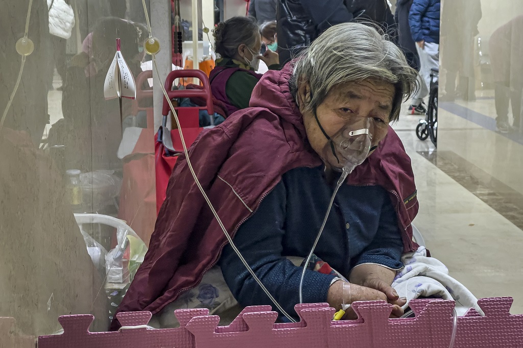 An elderly patient receives an intravenous drip while using a ventilator in the hallway of the emergency ward in Beijing, Thursday, January 5, 2023. Patients, most of them elderly, are lying on stretchers in hallways and taking oxygen while sitting in wheelchairs as COVID-19 surges in China's capital Beijing. (AP Photo/Andy Wong)