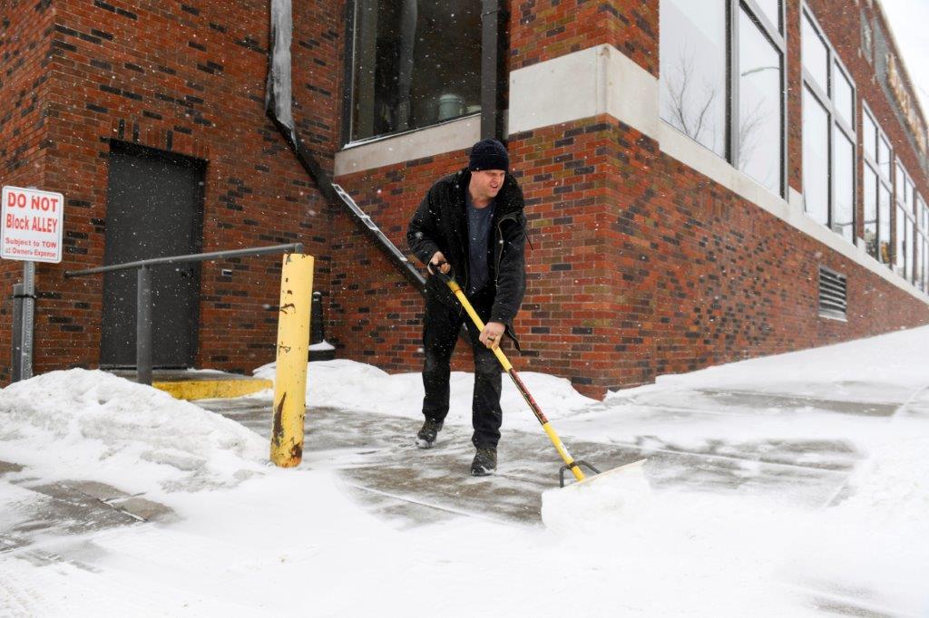 David Smith shovels the sidewalk as the first snow falls ahead of a winter storm on Tuesday, February 21, 2023, in Sioux Falls, South Dakota. A wide swath of the Upper Midwest is bracing for a historic winter storm. The system is expected to bury parts of the region in two feet of snow, create dangerous blizzard conditions and bring along bitter cold temperatures. (Erin Woodiel/The Argus Leader via AP)