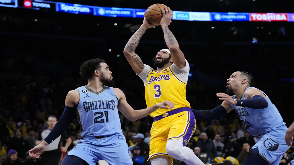 Los Angeles Lakers' Anthony Davis (3) goes up for a basket past Memphis Grizzlies' Tyus Jones (21) and Dillon Brooks (24) during the first half of an NBA basketball game Tuesday, March 7, 2023, in Los Angeles. (AP Photo/Jae C. Hong).
