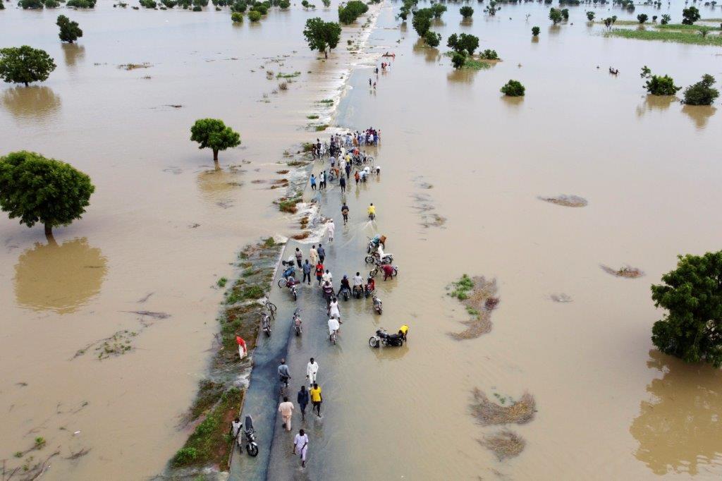 FILE - People walk through floodwaters after heavy rainfall in Hadeja, Nigeria, September 19, 2022. Publication of a major new United Nations report on climate change is being held up by a battle between rich and developing countries over emissions targets and financial aid to vulnerable nations. (AP Photo, File)