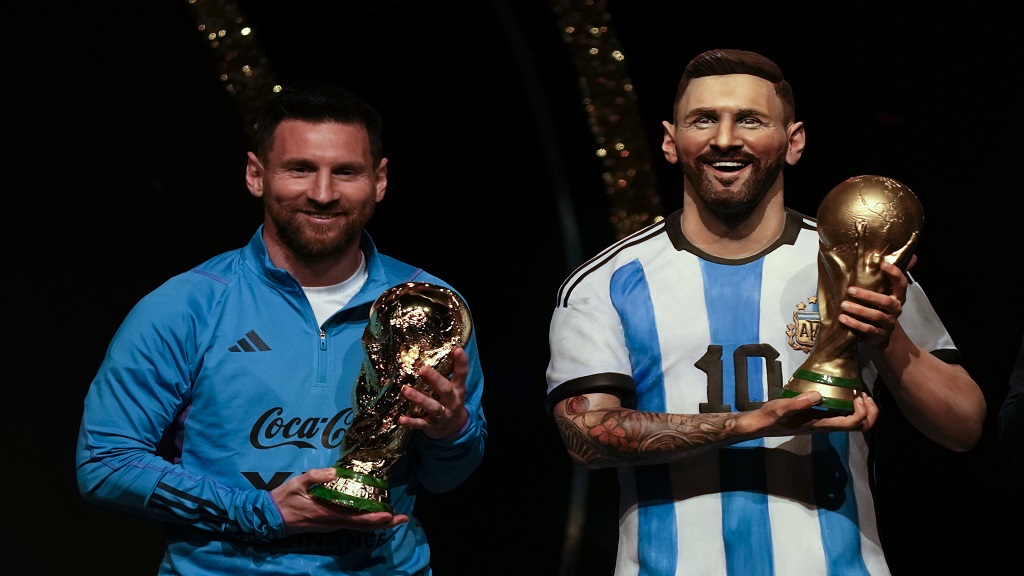 Argentina's football star Lionel Messi holds a replica of the FIFA World Cup trophy next to a statue of himself during a ceremony at the CONMEBOL headquarters in Asuncion, Monday, March 27, 2023. CONMEBOL authorities held a ceremony to honour the Argentine squad after they won the World Cup, prior to the draw for the group stage of Libertadores and Sudamericana tournaments. (AP Photo/Jorge Saenz).
