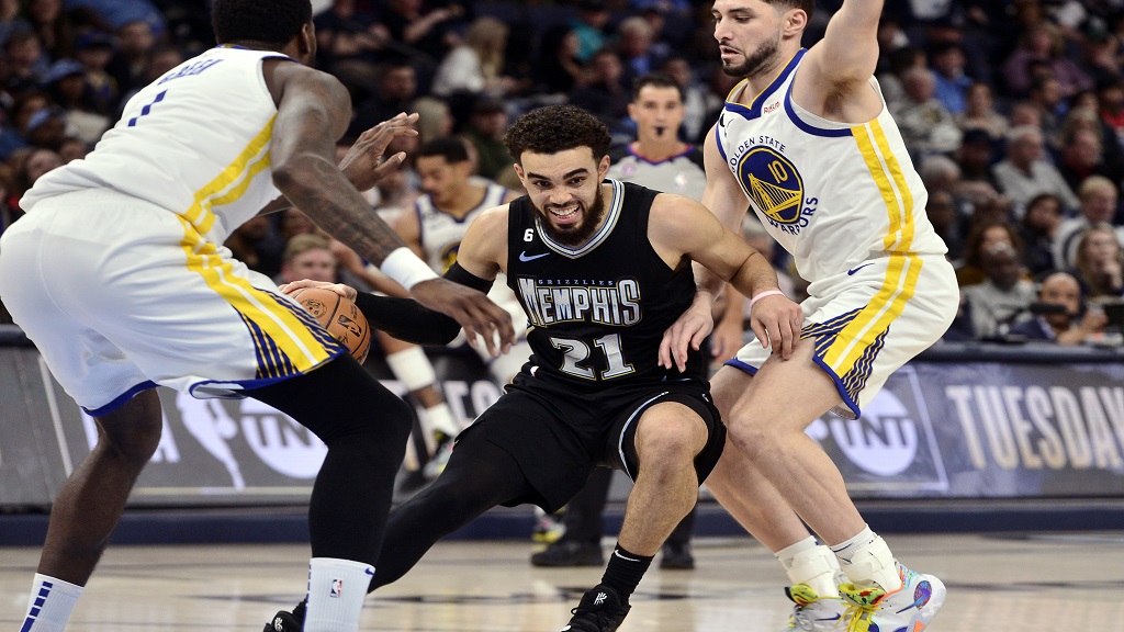 Memphis Grizzlies guard Tyus Jones (21) works between Golden State Warriors guard Ty Jerome, right, and forward JaMychal Green during the second half of an NBA basketball game Thursday, March 9, 2023, in Memphis, Tenn. (AP Photo/Brandon Dill).
