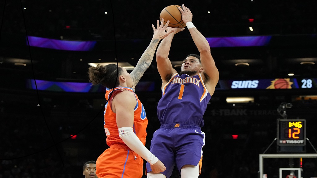 Phoenix Suns guard Devin Booker shoots over Oklahoma City Thunder forward Lindy Waters III during the first half of an NBA basketball game, Wednesday, March 8, 2023, in Phoenix. (AP Photo/Rick Scuteri).
