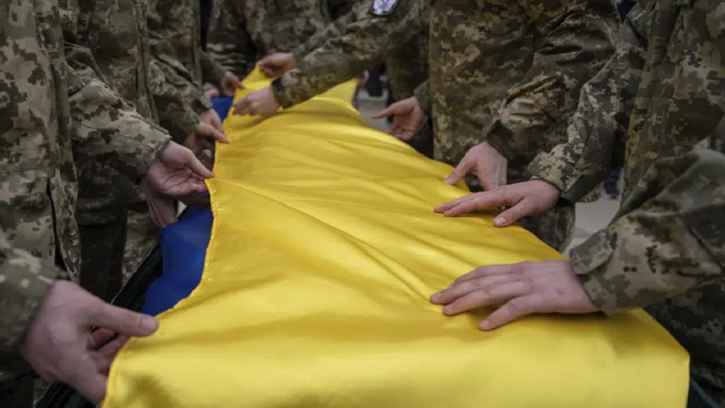 Ukrainian servicemen fold the national flag over the coffin of their comrade Andrii Neshodovskiy during the funeral ceremony in Kyiv, Ukraine, Saturday, March 25, 2023. (AP Photo/Evgeniy Maloletka)