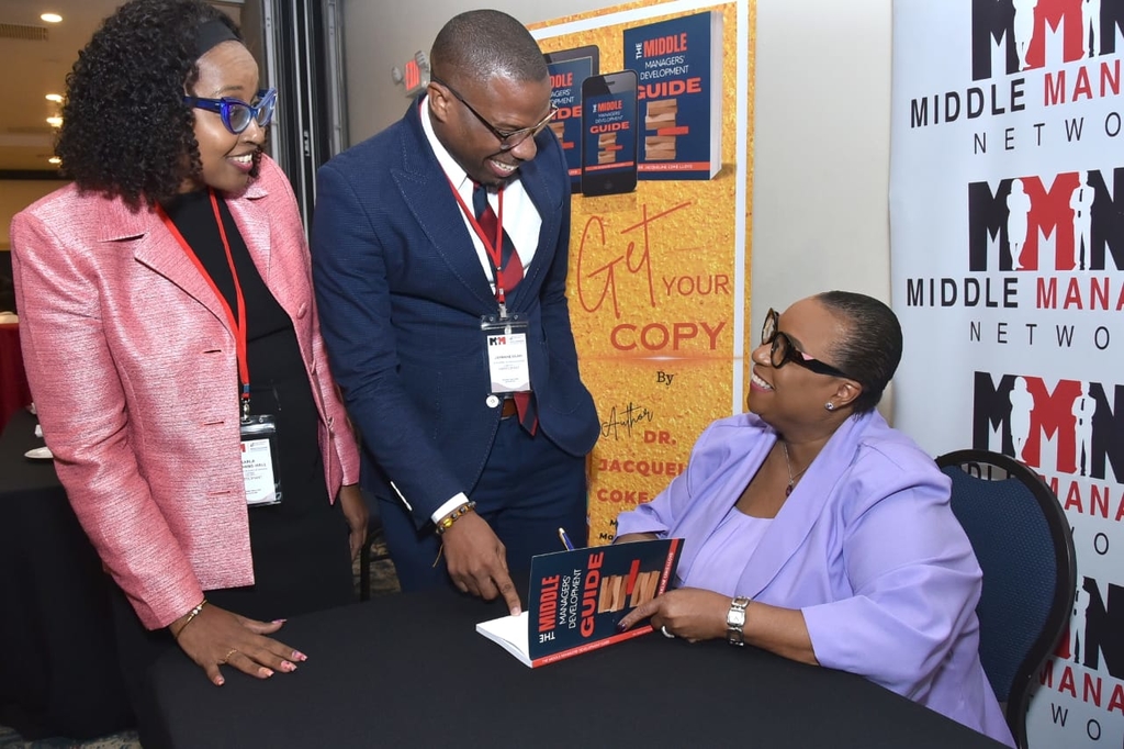 Dr Jackie Coke-Lloyd (seated), Managing Director of Make Your Mark Group (MYMG) converses with Karla Stephens-Hall, Financial Officer at Progressive Grocers of Jamaica Ltd and Jermane Blair, Branch Manager, Courts Portmore as she signs her book, The Middle Managers Development Guide at the Jamaica Pegasus Hotel on Wednesday, April 26. The book was launched at the Middle Managers Leadership Conference 2023 which is staged by MYMG.