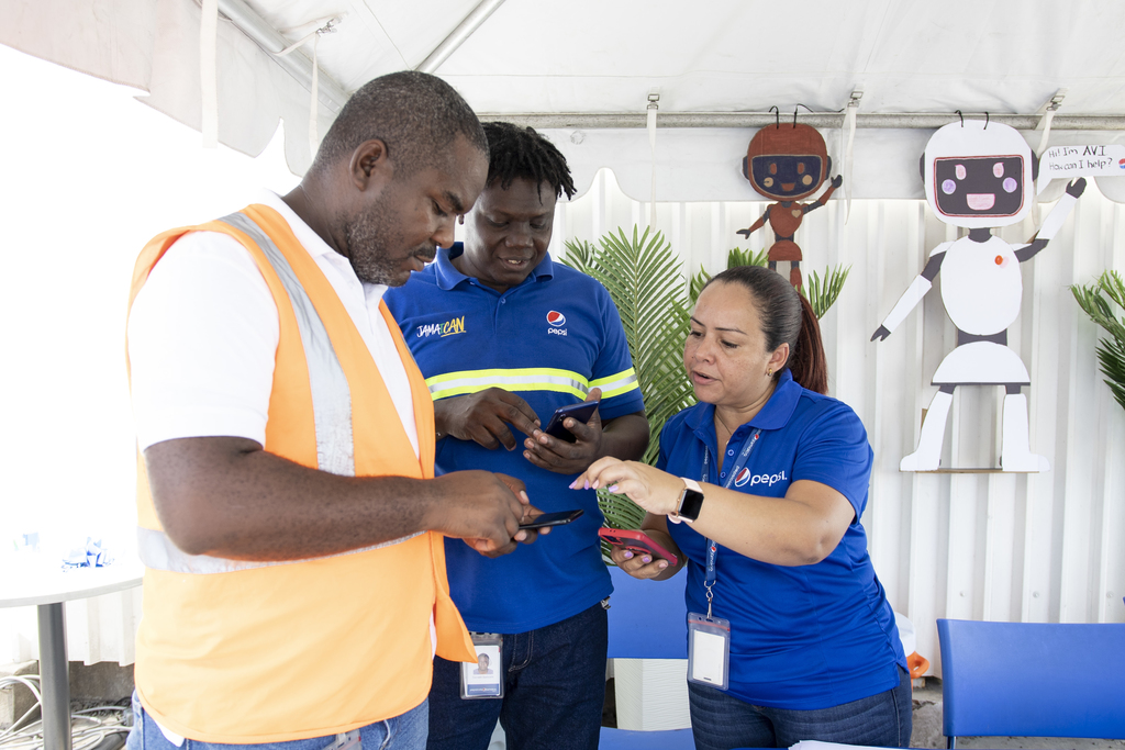 Pepsi Cola Jamaica HR Specialist Jaquelin Bolanos explains to Damion Thompson, Compliance and Control Chief, and Garnett Samuels,
Maintenance Technician, how to access and use AVI.