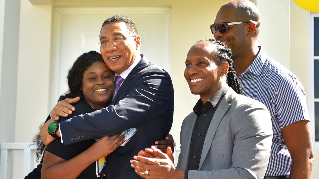 Prime Minister Andrew Holness (second left) embraces Shaniel Francis (left) after presenting her with the keys to her new three-bedroom house under the New Social Housing Programme (NSHP) at Casabanna in Clifton, St Catherine, on December 19 . Sharing the moment are Member of Parliament for St Catherine East Central, Alando Terrelonge (right), and Member of Parliament, St Catherine South Eastern, Robert Miller. (Photo: JIS)