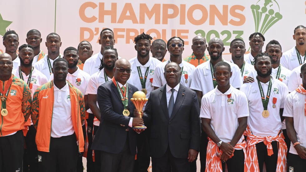 The president of the Ivorian Football Federation Yacine Idriss Diallo (l) and the president of Côte d'Ivoire Alassane Ouattara with the CAN winners' cup, the Ivorian Elephants, invited during a ceremony at the presidency on February 13 2024 in Abidjan ISSOUF SANOGO / AFP  