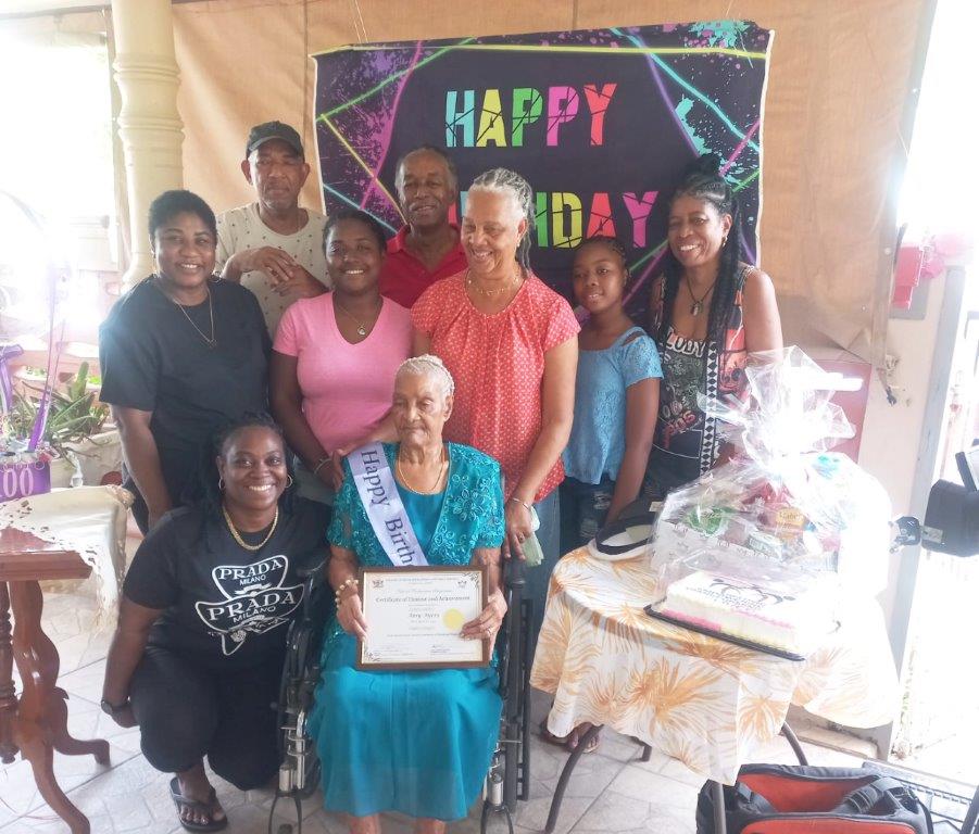  Amy Ayers celebrates her 100th birthday with loved ones. Image courtesy the Ministry of Social Development and Family Services.