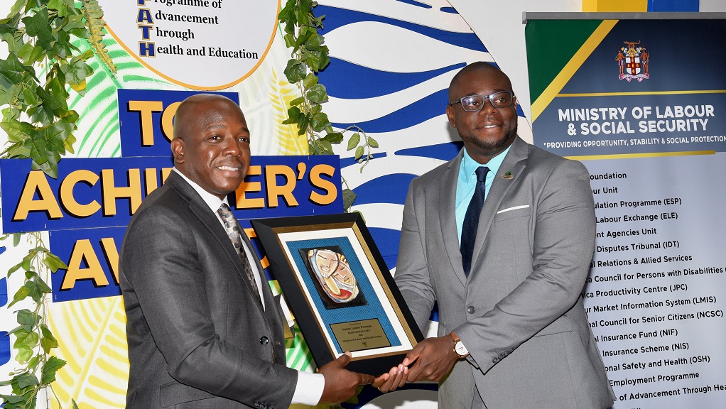 Minister of Labour and Social Security Pearnel Charles Jr (left) presents Jordon Freeman with the 2024 Programme of Advancement through Health and Education (PATH) Trailblazer Award, during the PATH Top Achiever’s Awards Ceremony at the Spanish Court Hotel in New Kingston on April 11. (Photo: JIS)