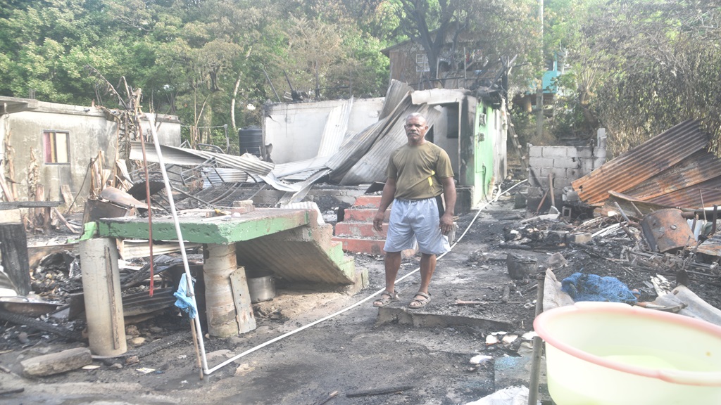 Evans William stands next to the ruins of his family home
