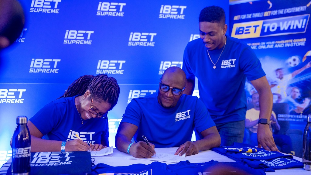 Guyanese superstar Rawle Toney (centre) officially joins iBet Supreme Guyana as its first-ever brand ambassador, signing alongside Abigail Primo-Chase (left), general manager, and Omar Dattadeen, senior marketing manager, at the UEFA Champions League watch party held at Froggy’s Grill in Georgetown recently.