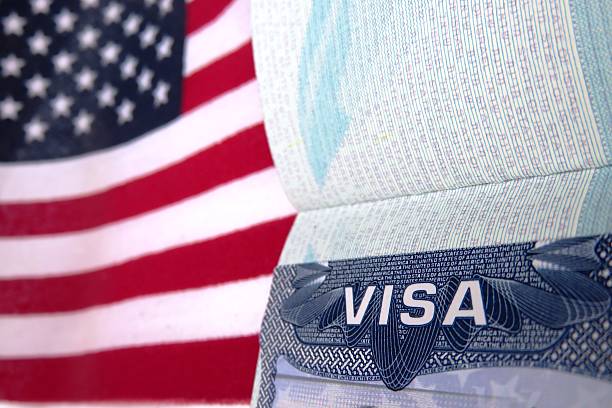 Passeport avec visa ouvert sur un drapeau américain | iStock