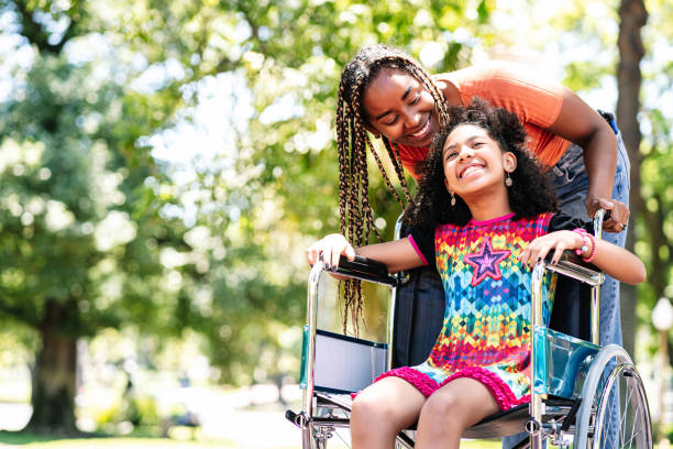 Little girl in a wheelchair at the park with her mother.  Photo: iStock.