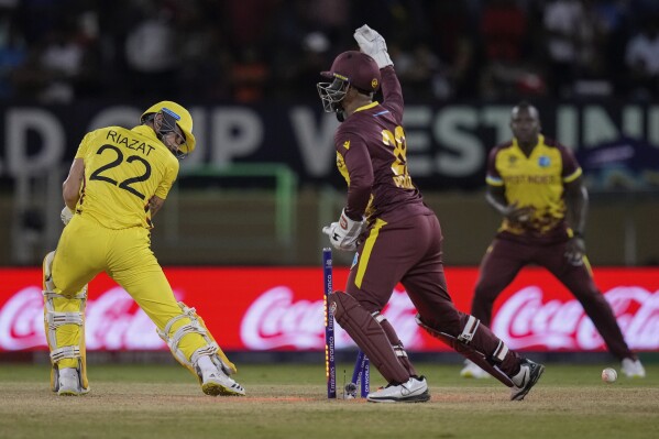 Uganda’s Riazat Ali Shah, left, watches his wicket as he’s clean bowled by West Indies’ Akeal Hosein for 3 runs during an ICC Men’s T20 World Cup cricket match at Guyana National Stadium in Providence, Guyana, Saturday, June 8, 2024. (AP Photo/Ramon Espinosa)