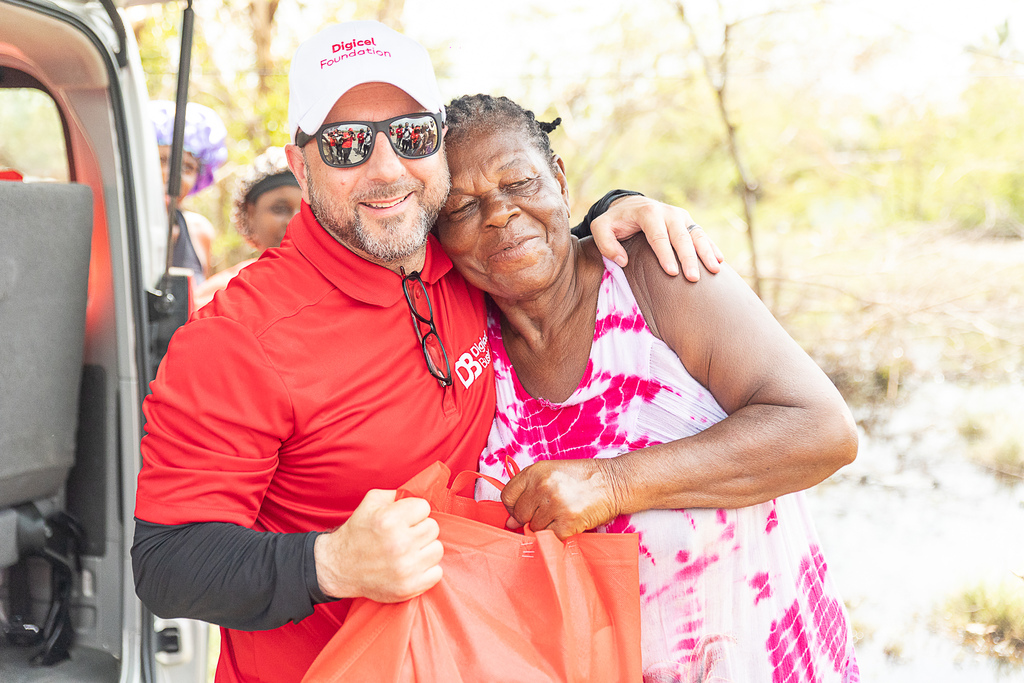 CEO of Digicel Jamaica, Stephen Murad embraces Parottee resident affectionately called “Mama Bennett” as she accepts a care package from the Digicel Foundation during the recent hurricane relief initiative in St Elizabeth. 