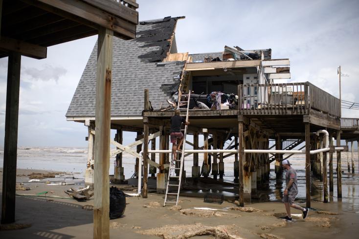 Mike Isbell (center) climbs a ladder to view the remains of his destroyed home after Hurricane Beryl in Surfside Beach, Texas, on July 8, 2024 MARK FELIX / AFP 