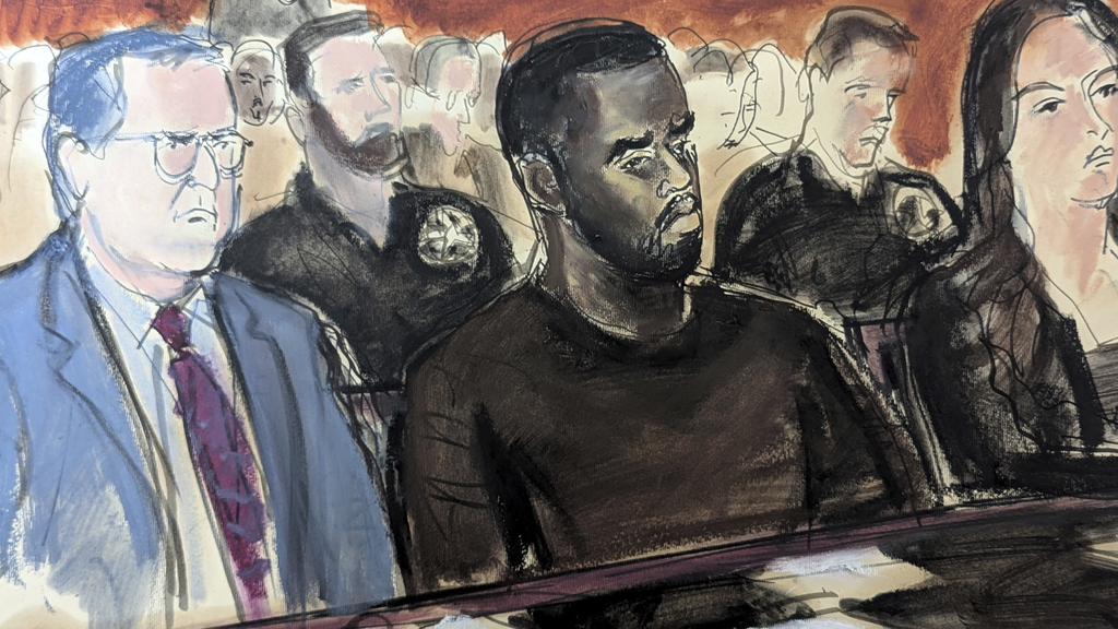 In this courtroom sketch, Sean Combs, seated right, looks at his attorney, Marc Agnifilo, left, as he delivers his bail argument as Combs' family in the gallery, background, raise their hands indicating to Judge Tarnofsky that they are in attendance, to bolster the defence attorney's bail argument, Tuesday, Sept. 17, 2024, in Manhattan Federal Court in New York. (Elizabeth Williams via AP)
