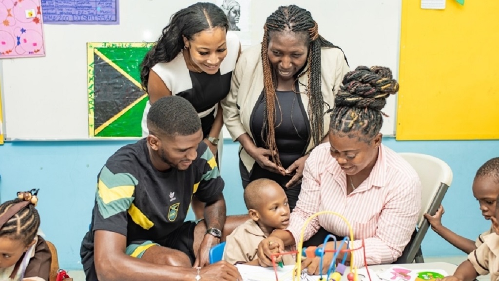 Damion Lowe (left) and a teacher interact with a student at the Early Childhood Centre, joined by Dominique Walker, CEO of PrintWare Group, and principal Antonica Gunter-Gayle. (PHOTO: Contributed).