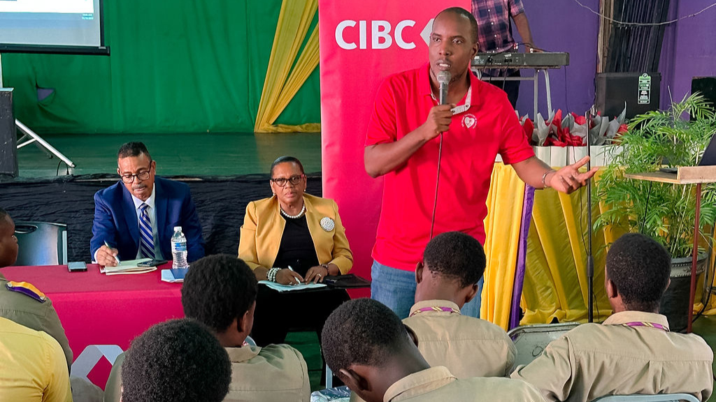 Speaker Alonzo Mothersill, Emergency Cardiac Care Training Manager addressing students at CIBC Caribbean's Men's Health Champions Fair in celebration of International Men's Day at Pembroke Hall High School on Tuesday, November 19, 2024.  Looking on are the bank's Managing Director, Nigel Holness and Head of Human Resources, Jerome Griffiths.