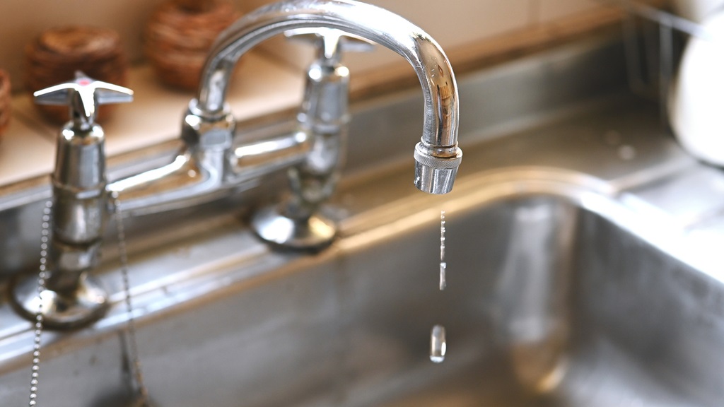 iStock photo depicting a leaking tap in the kitchen, faulty faucet and water dripping.