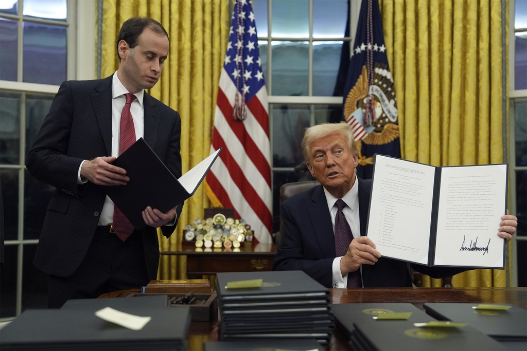 President Donald Trump holds up an executive order commuting sentences for people convicted of Jan. 6 offenses in the Oval Office of the White House, Monday, January 20, 2025, in Washington. (AP Photo/Evan Vucci)
