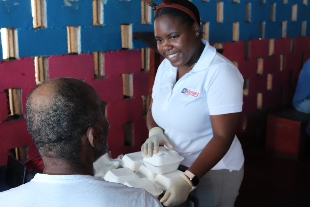 Shanique Tomlinson (right)  of JN Money serves lunch to a resident of the Marie Atkins Night Shelter during the remittance company's annual luncheon at the Marie Atkins Night Shelter recently.
