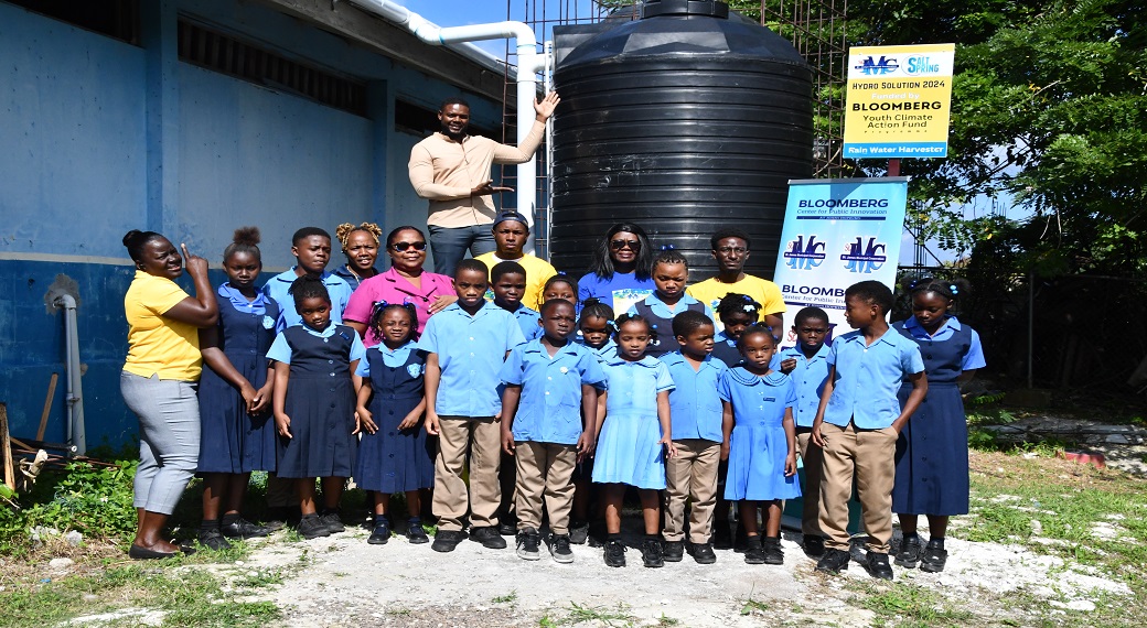 Mayor of Montego Bay, Councillor Richard Vernon (in background), with students of the Salt Spring Primary and Infant School after a 1000-gallon water tank was installed.