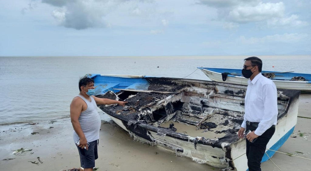 卡莉湾渔民展示了一艘被怀疑是在纵火袭击中被毁的船只，国会议员在一旁观看。