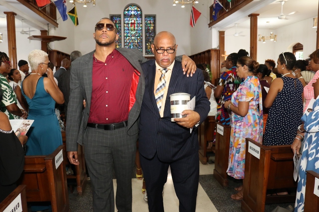 Michael Erskine (right), husband of Marcia Erskine and Machel Erskine (son) exit the UWI Chapel following the thanksgiving service on April 13. 