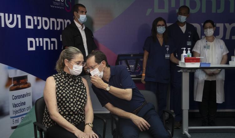 2021年7月30日星期五，以色列总统艾萨克·赫尔佐格在以色列拉马特甘的谢巴医疗中心接受第三次冠状病毒疫苗前与妻子米歇尔(左)交谈。(美联社图片/Maya Alleruzzo, Pool)