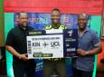 Gary Peart, executive chairman of Supreme Ventures Limited (left), and SportsMax sales representative Wayne Lewis (right) present a symbolic boarding pass to Pepetho Barrett, the grand prize winner of an all-expenses-paid trip for two to the UEFA Champions League final at Wembley Stadium in London. The presentation took place during the JustBet lyme event at Sabina Park on Sunday, May 12, 2024. (PHOTO: Contributed).